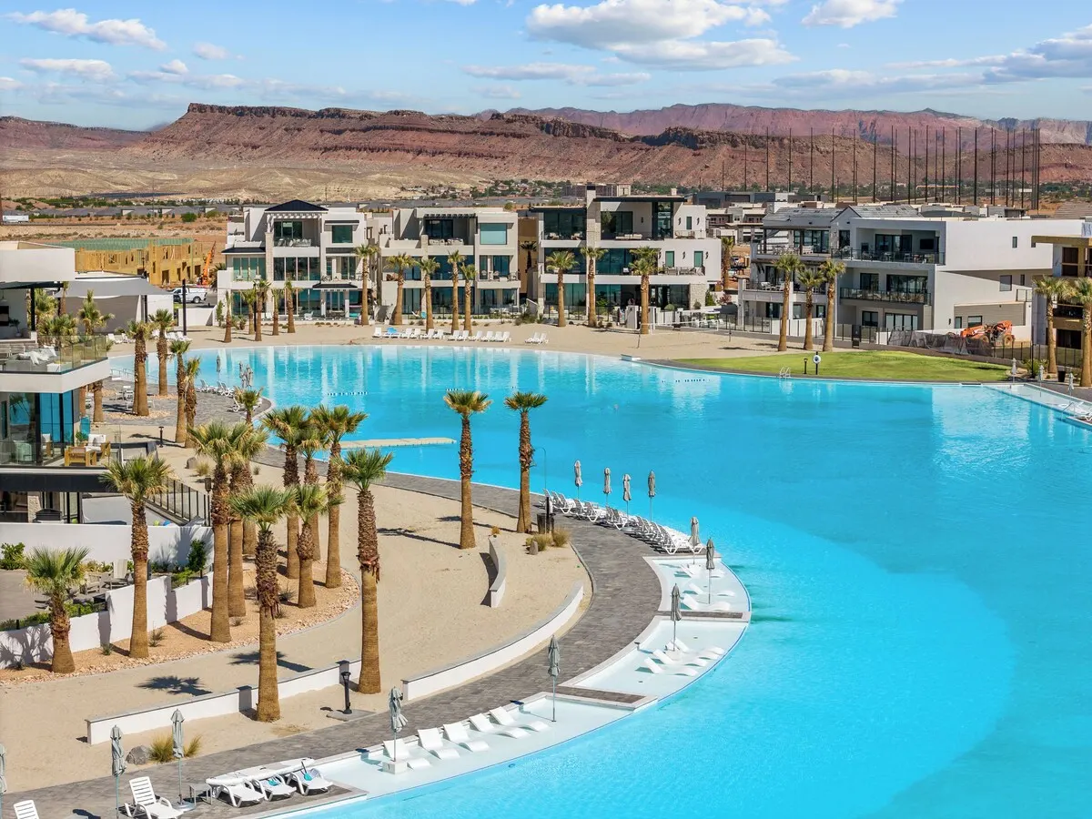 Lagoon-front homes with in-water lounge chairs and red cliffs behind