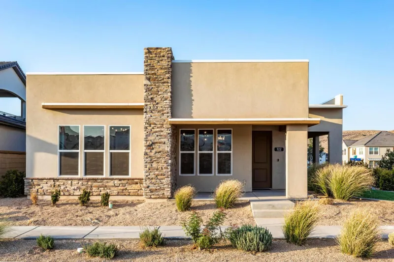 Single-level Holmes single-family home with a stone chimney and desert landscaping in Desert Color